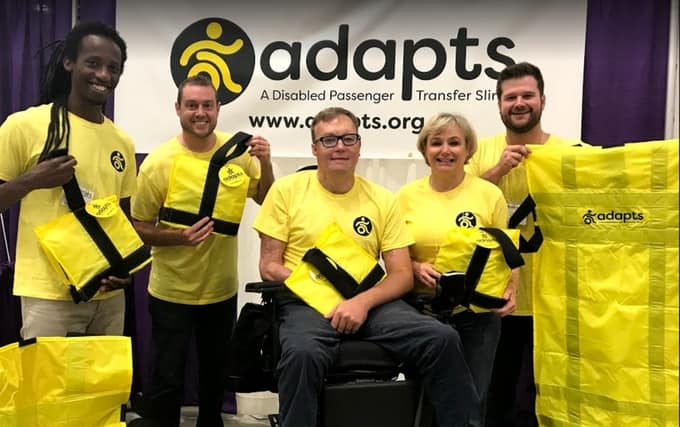 A group of people in yellow t-shirts holding ADAPTS slings.