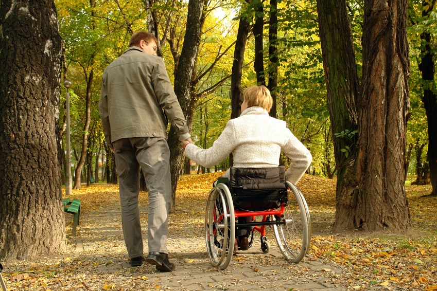 Husband and handicapped wife taking stroll in park alley