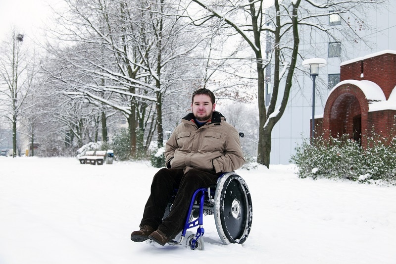 young man in wheelchair at the park on a cold winterday