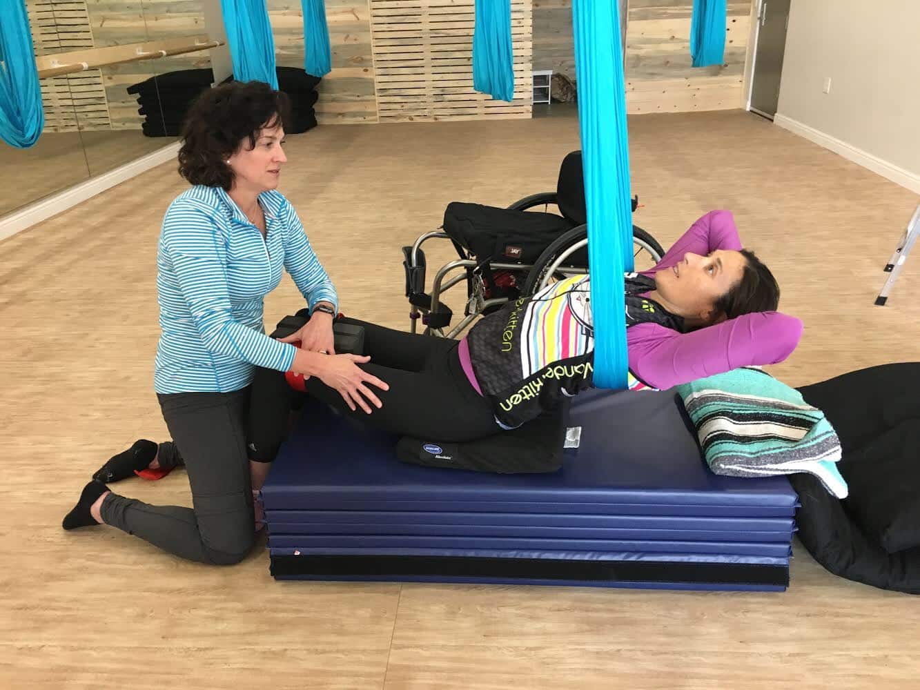 woman and instructor doing adaptive aerial yoga