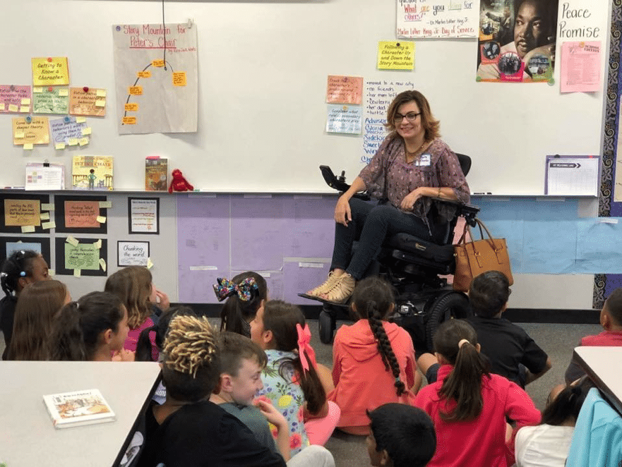 Margarita Elizondo in wheelchair at head of class with school children listening