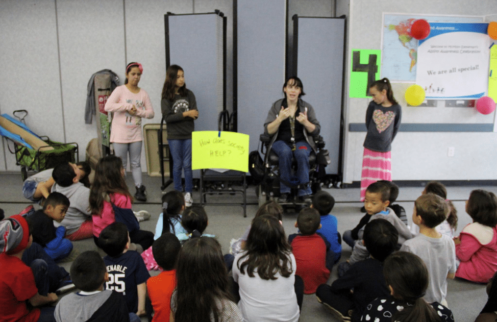 Woman in wheelchair talking to children in classroom