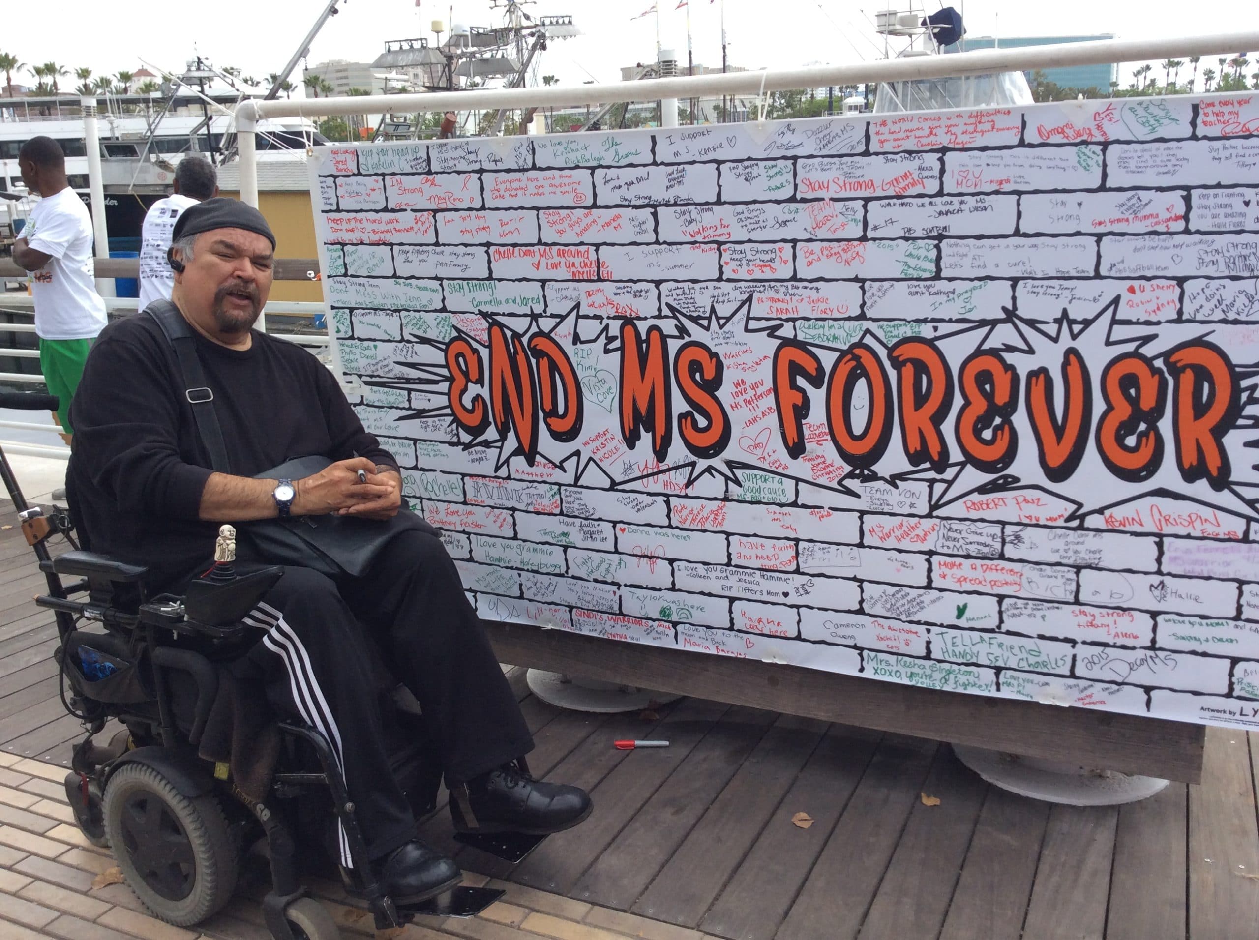 Carlos by a sign that says "End MS Forever"