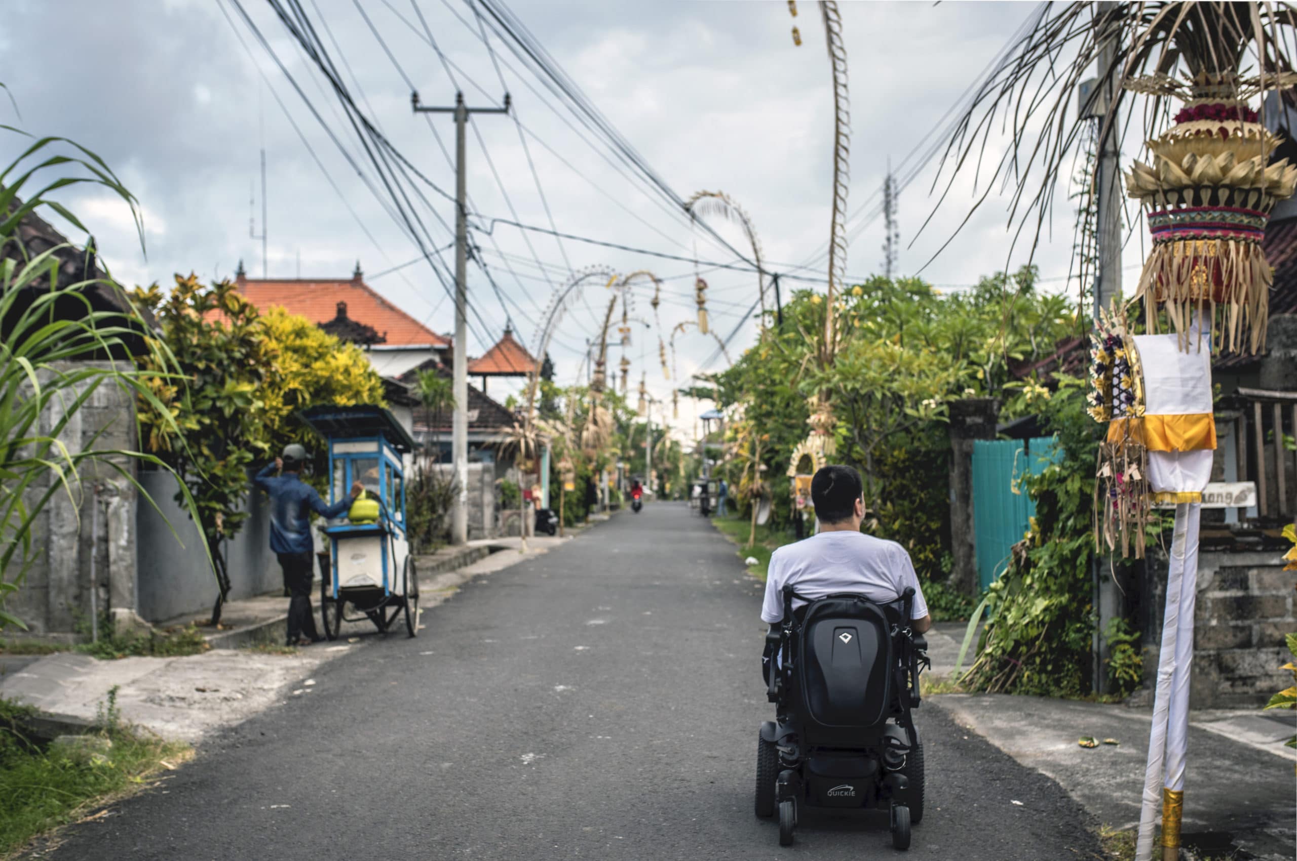 Minna riding down a street in Bali in his wheelchair