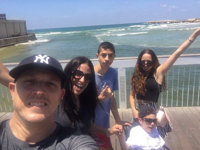 Erez with his family on a boardwalk overlooking the sea