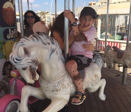 Erez rides a merry-go-round with the support of a woman