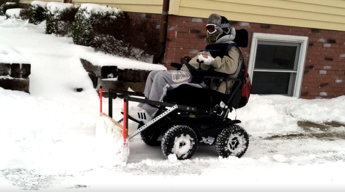 Tim Taylor plows snow with his 4x4 wheelchair and plow attachment he designed.