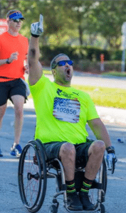 Luis at a race with his hand up in the air celebrating.