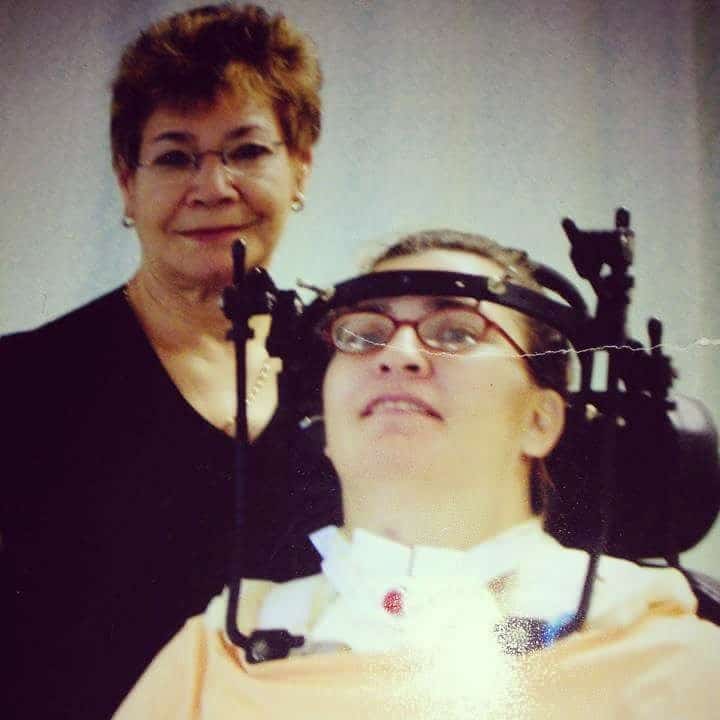 A woman is standing behind another woman wearing a head brace after a spinal cord injury,