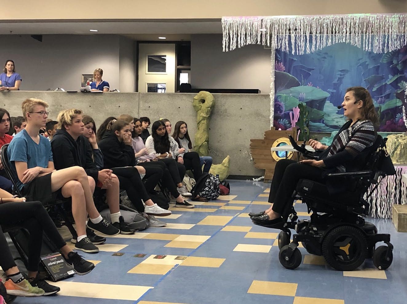 Margarita Elizondo in a power chair addressing a group of students in a classroom.