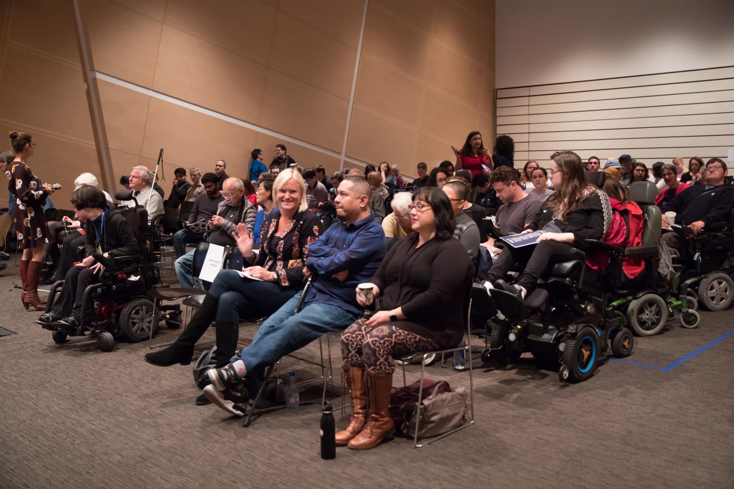A group of people, some in wheelchairs, sitting in a room for a Superfest screening.