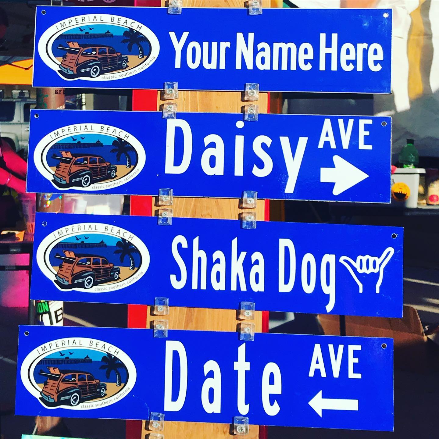Blue signs reading, "Your Name Here," "Daisy Ave," Shaka Dog," and Date Ave."
