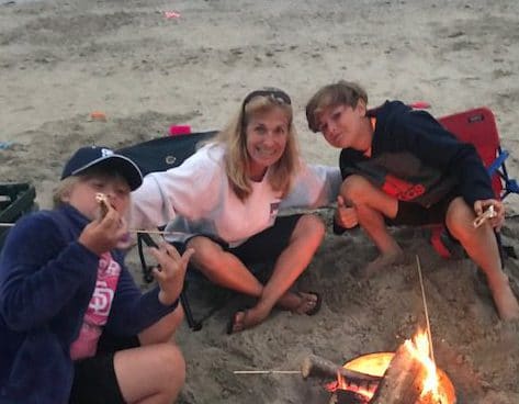 The daughter, wife, and son of Stefan Freeman sitting around a camp fire on the beach.