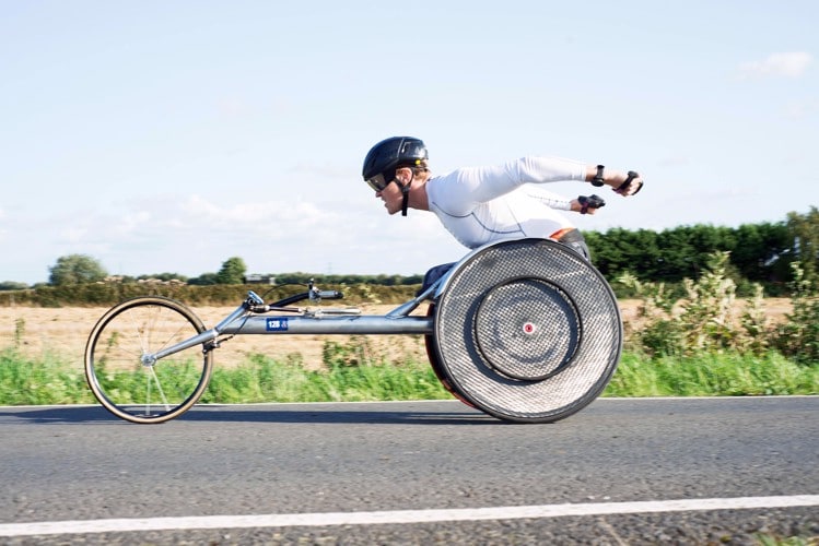 Josh Landmann racing down a street in a racing wheelchair.