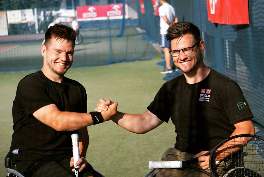 Max and Marcus at the tennis courts facing the camera smiling and locking hands.