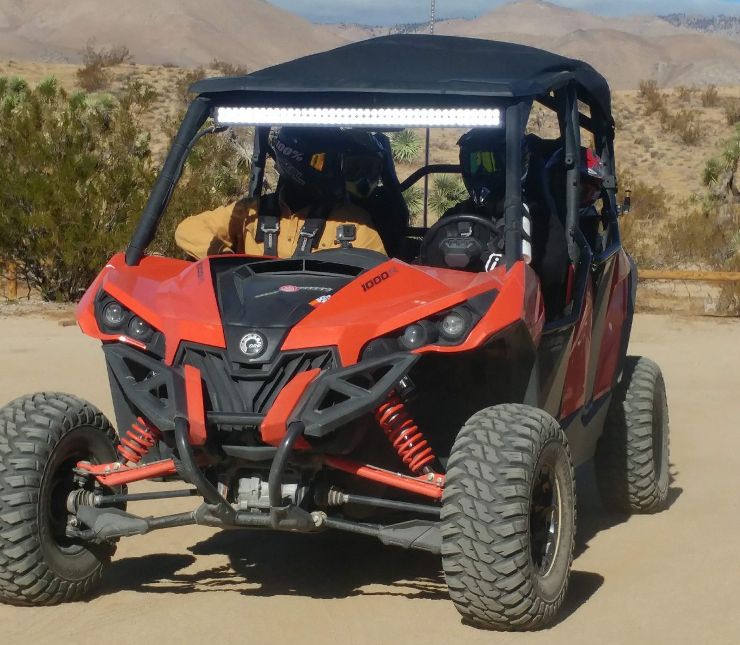 Two people in a 4-wheeled dune buggy on the sand.