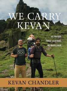 Book cover for We Carry Kevan. It shows three men: one standing with walking sticks and carrying Kevan in a backpack, and the other standing next to them on a green, grassy hill.