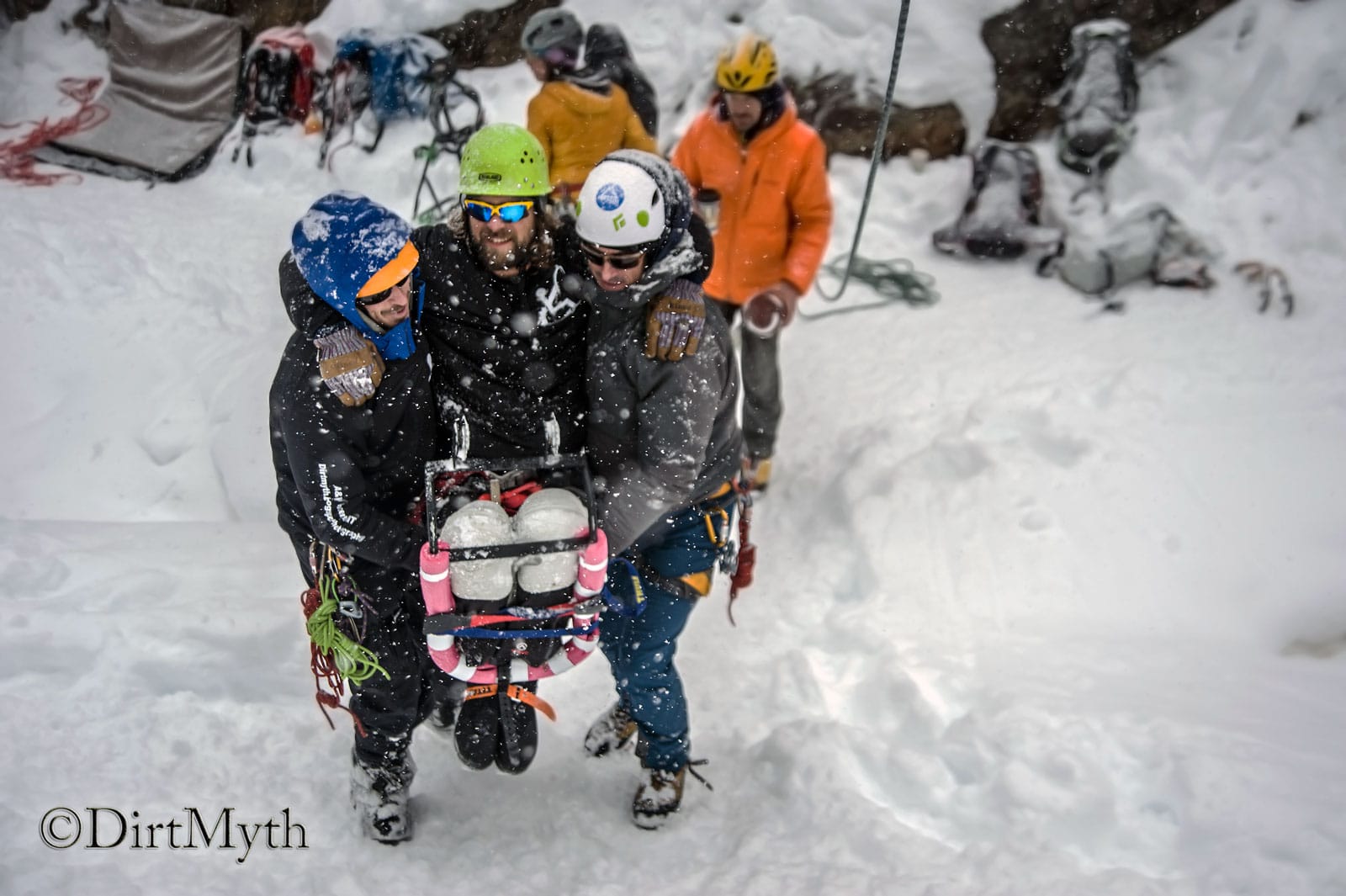 Two men carry another man up a snowy hill.